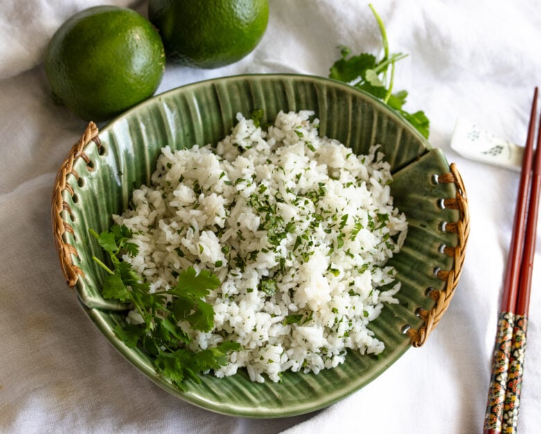 rice in a green dish with red chopsticks