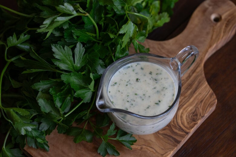 parsley sauce on a wooden board with fresh parsley around it