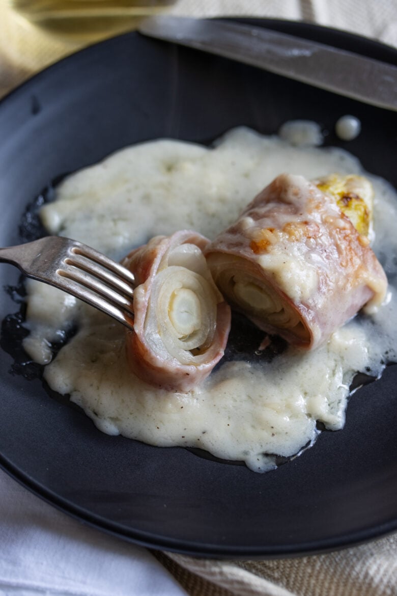 Endive Ham Gratin  in a black plate with fork and cut