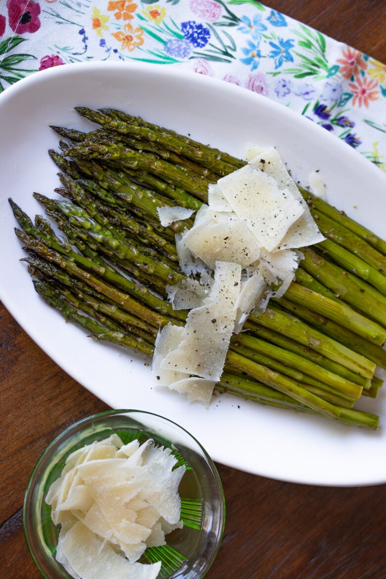 Roasted Parmesan Asparagus on a white plate with cheese shaving in a dish