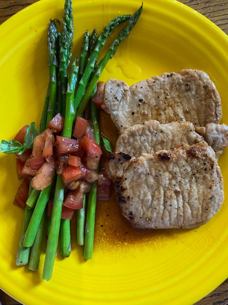 Asparagus with tomotoes balsamic vinaigrette served alongside small pork chops