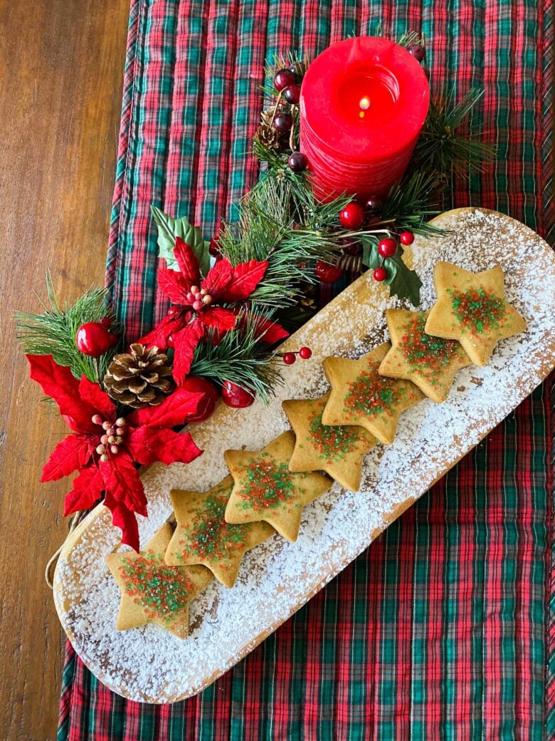 brown sugar cookies on a white dish with christmas holly around it and a red candle