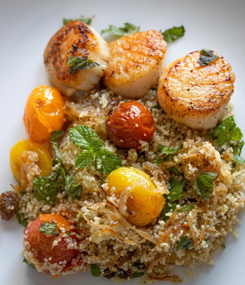 Couscous, Herbs, Tomatoes Salad with Scallops on a white plate