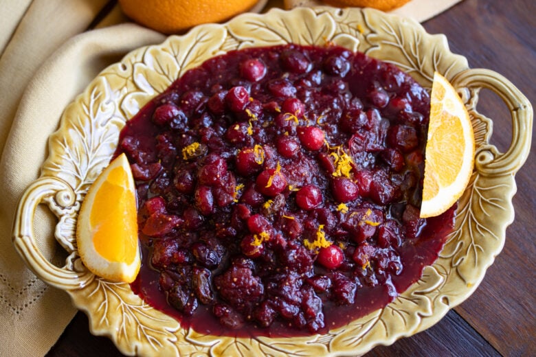 cranberry chutney with red winer in a mustard color plate with orange wedges