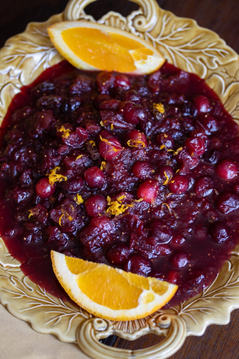 cranberry chutney with red wine in a serving plate with orange wedges