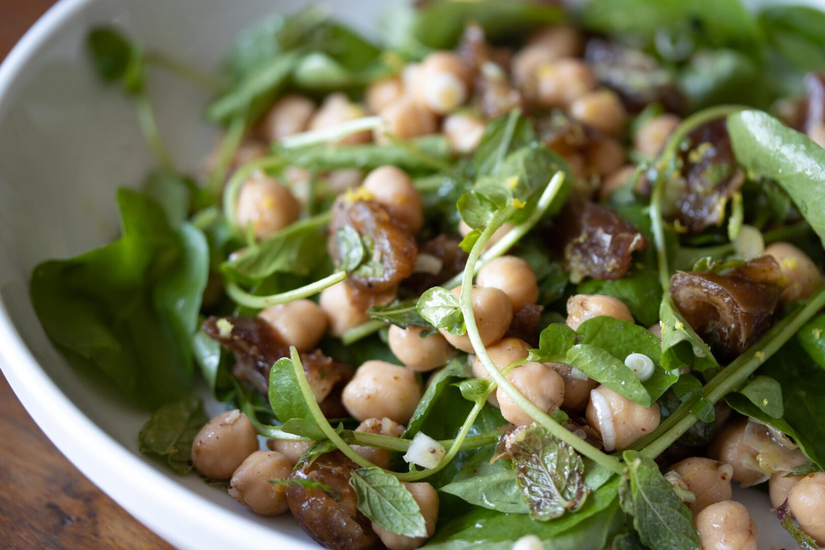 cresson, garbanzo beans, dates salad on a whilte serving palte