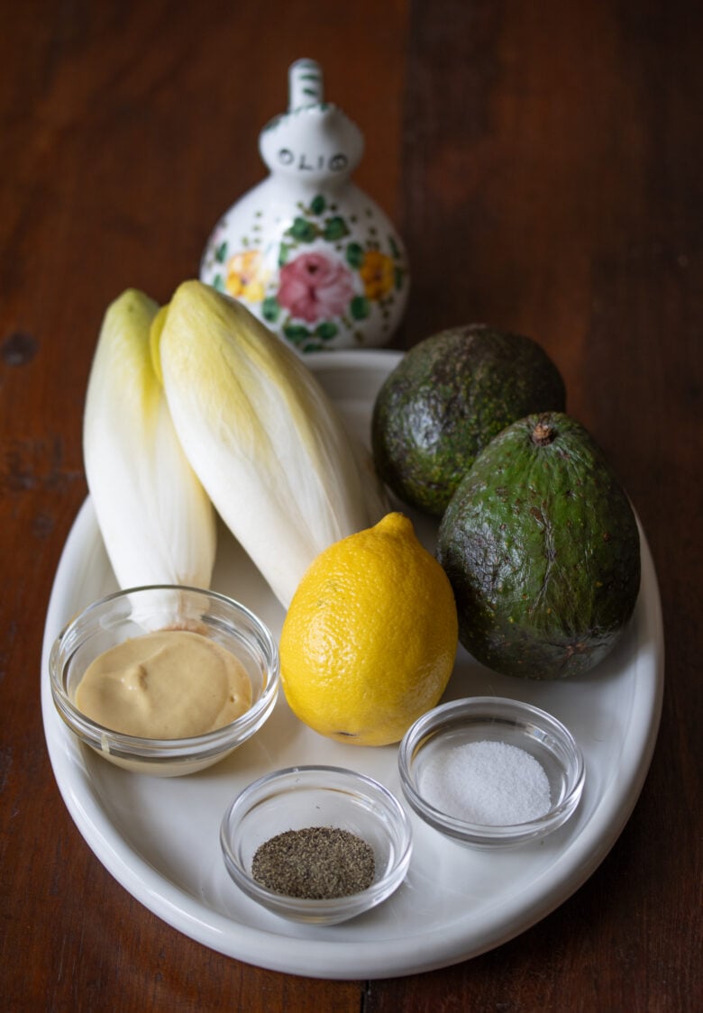 Belgian endive avocado salad ingredients on a white plate, 