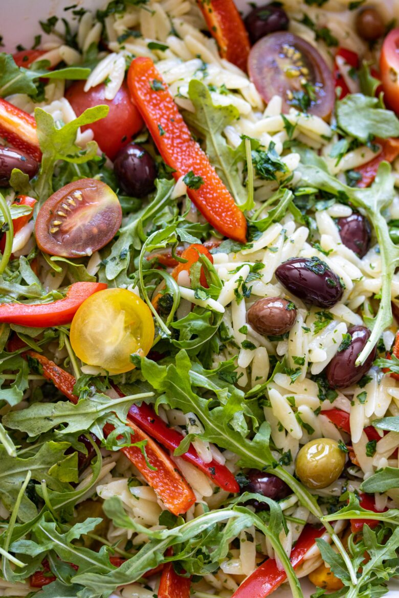 Orzo pasta salad with basil pesto, peppers, tomatoes close up