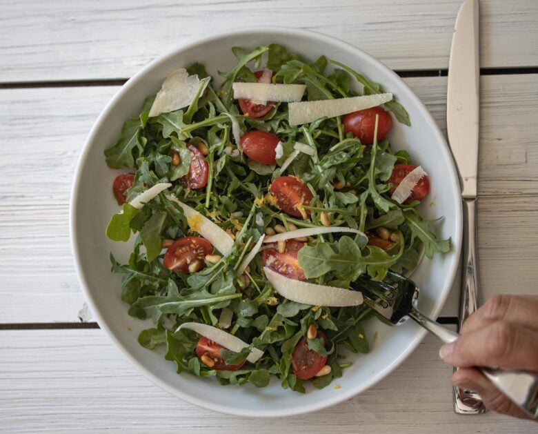 tomato arugula salad in a white plate ready to be enjoyed.