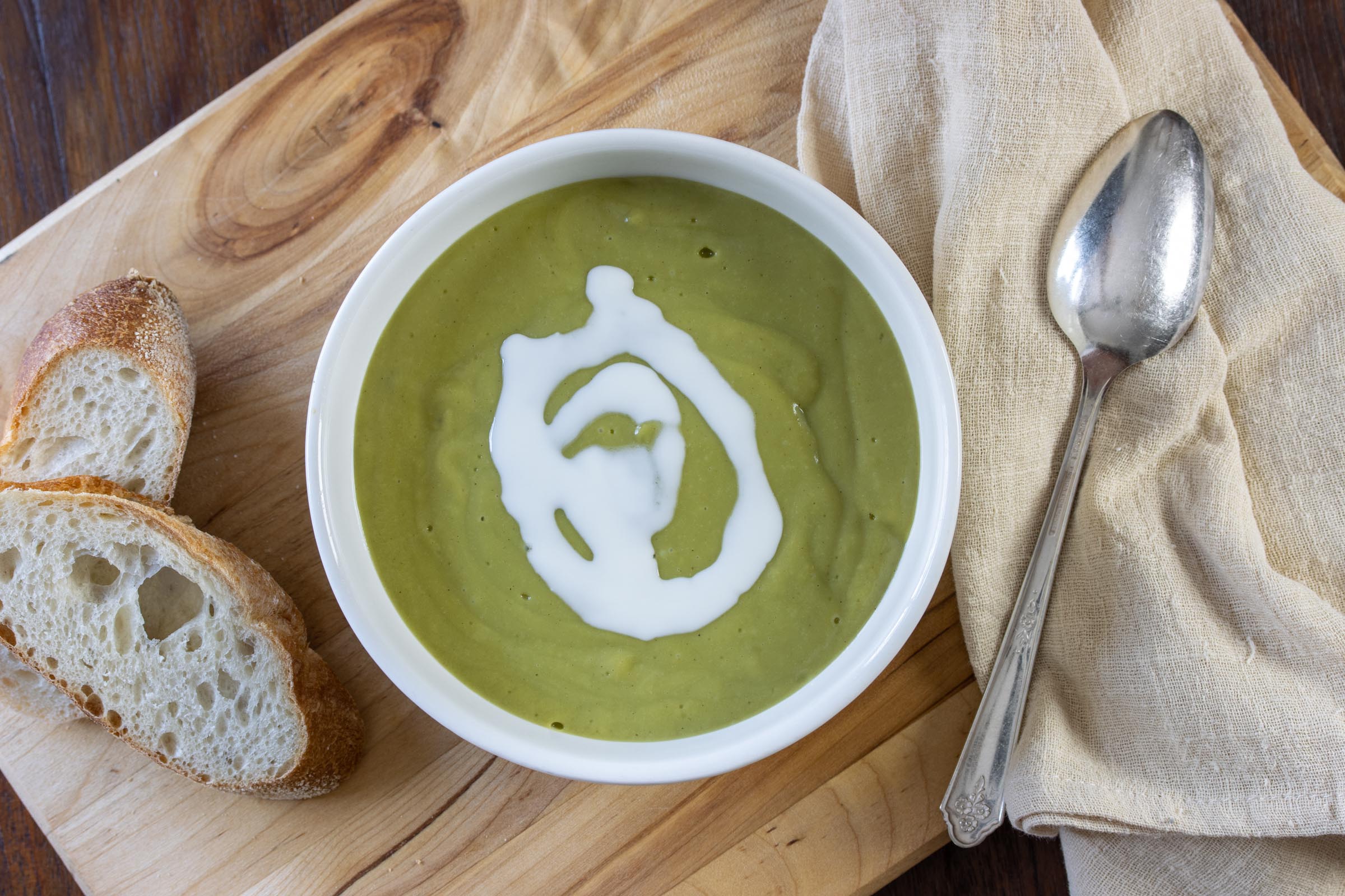 Creamy Watercress Soup in a bowl with bread and a spoon