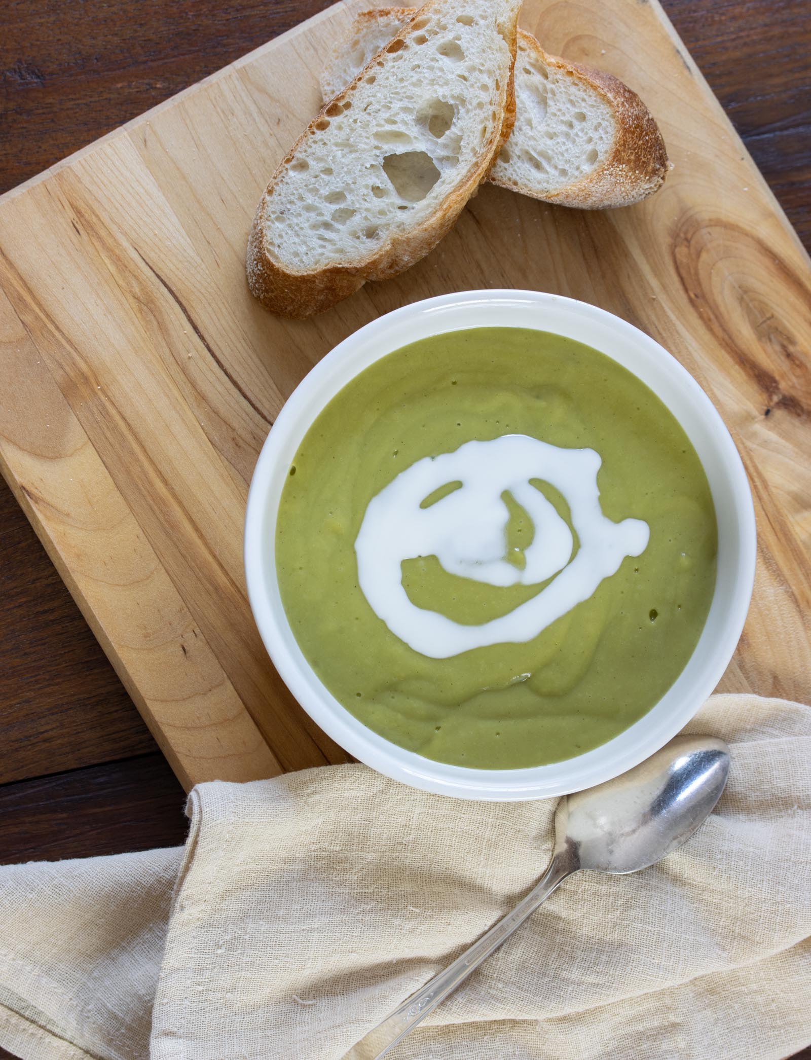 Creamy Watercress Soup on as board served alongside bread, napkin and spoon