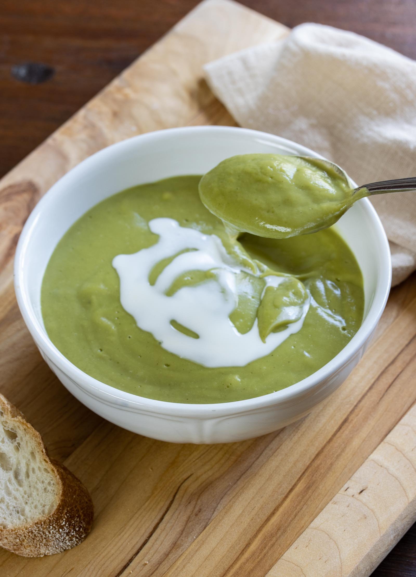 a spoonful of Creamy Watercress Soup on as board served alongside bread, napkin 